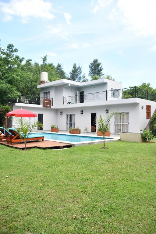 a white house with a swimming pool in the yard at Rincón de Rodríguez in General Rodríguez