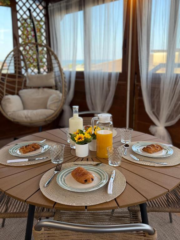 a wooden table with plates of food and orange juice at SvEly House B&B in Campomarino