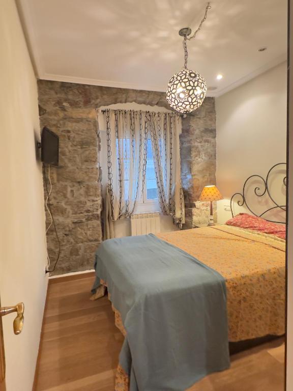 a bedroom with a bed and a stone wall at Encanto Histórico 9 in Avilés