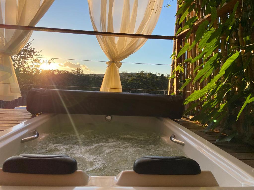 a jacuzzi tub with a view of the sunset at Chalé Makar - Hidromassagem aquecida e vista para as montanhas in Serra do Cipo