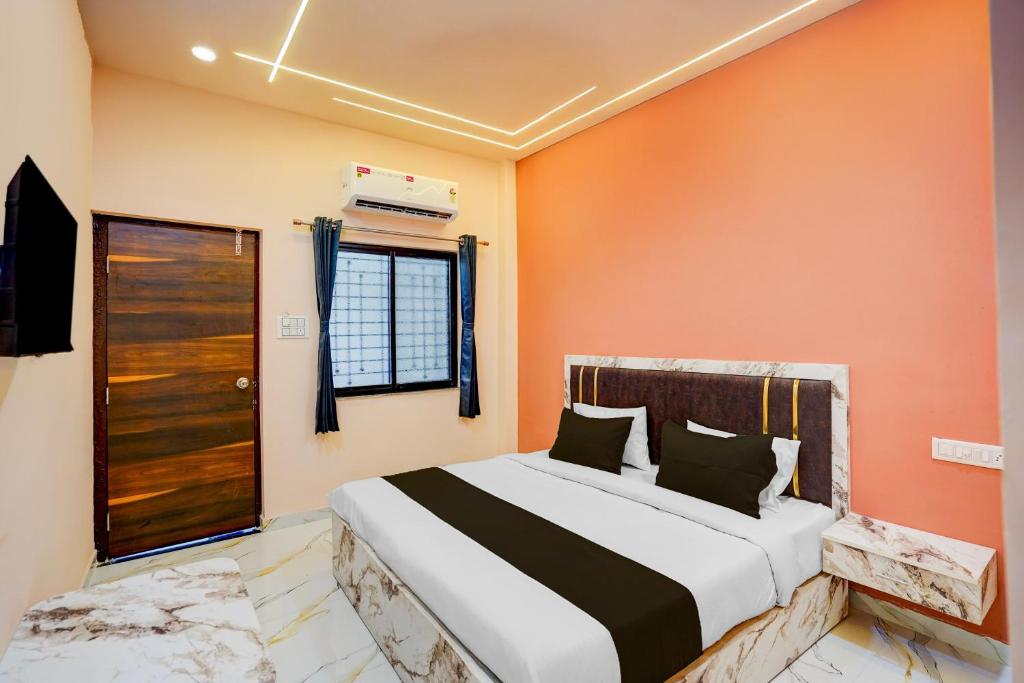 a bedroom with a bed with an orange wall at Hotel O DELIGHT INN in Chandrapur