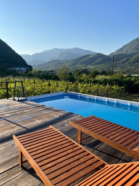 a pool with a table and benches on a deck at Rachuli blendi in Ambrolauri