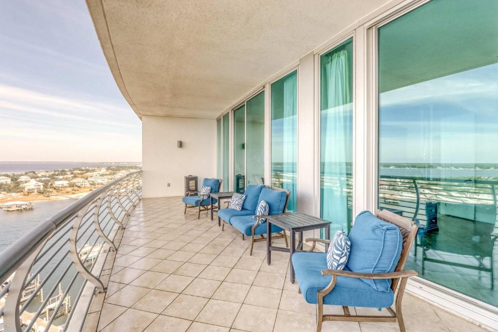 a balcony with blue chairs and a table and windows at Bella Luna 1203 in Orange Beach