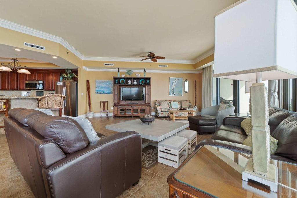 a living room with leather furniture and a tv at Phoenix West 2601 in Orange Beach