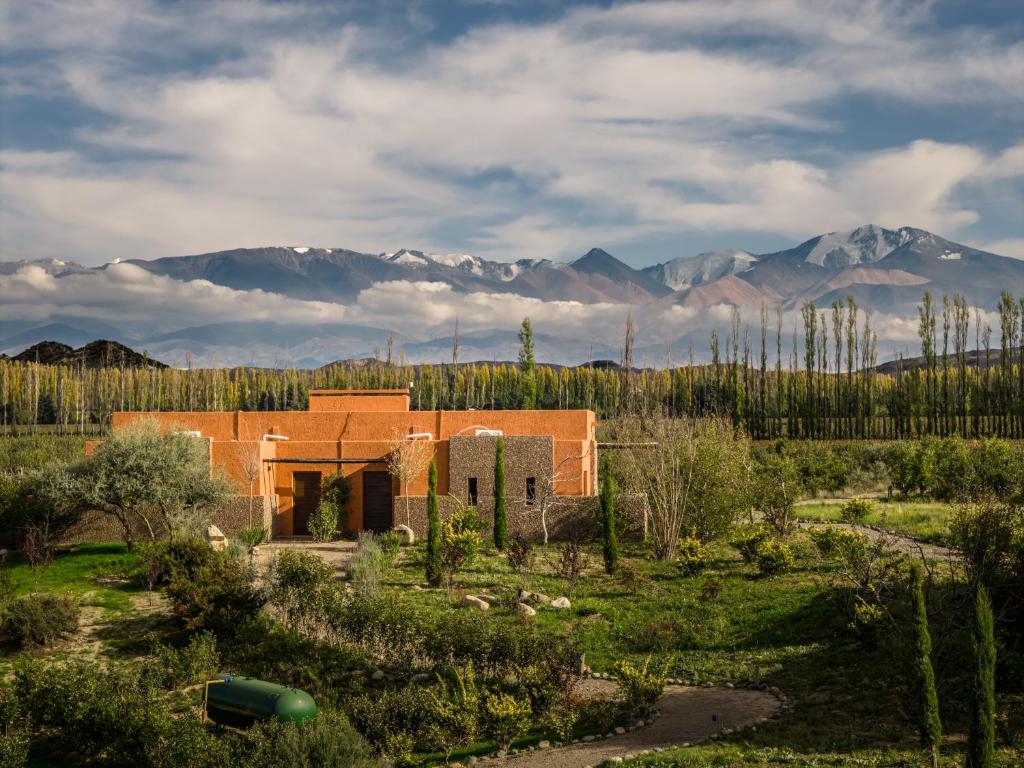 a house in a field with mountains in the background at Atamisque Wine Lodge - Valle de Uco in San José