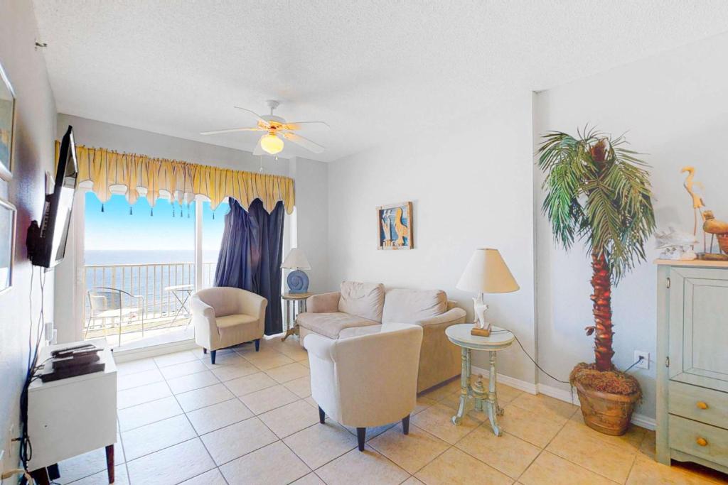 a living room with a couch and a palm tree at Tidewater 908 in Orange Beach
