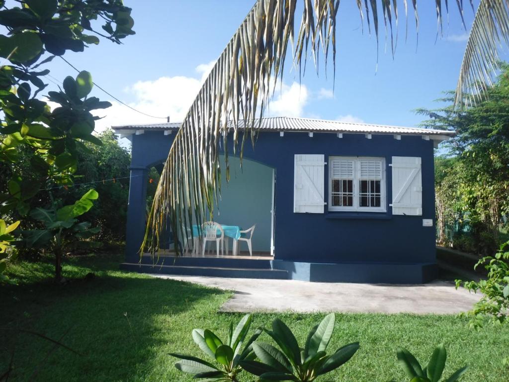a blue house with a chair in a yard at Bungalow cocodile in Sainte-Anne