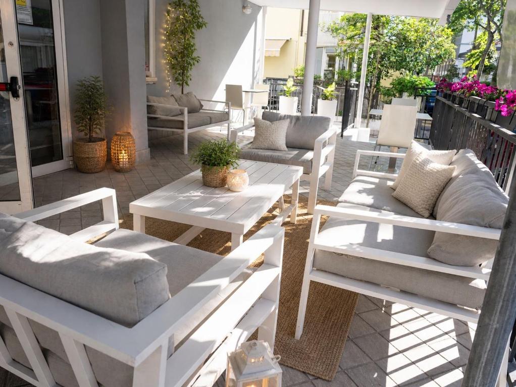 a group of white benches and tables on a patio at Residence Mareo in Riccione