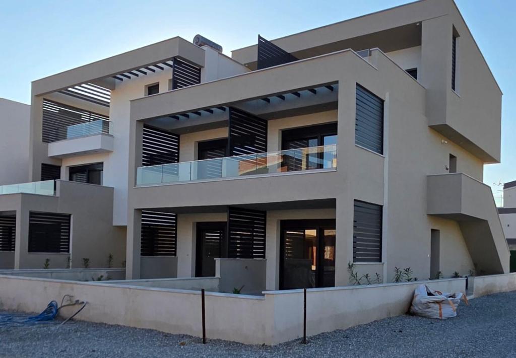 a large building with black shutters on it at Peralun Lux Apartments in Nea Peramos