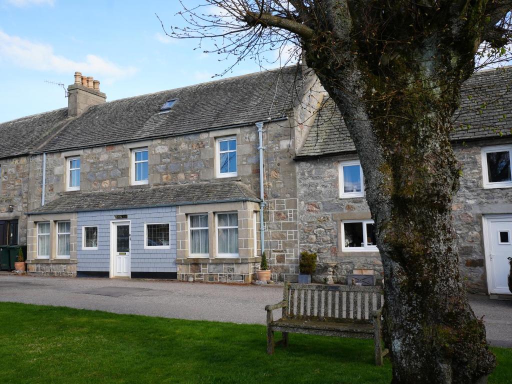 an old stone house with a bench in front of it at Cruachan B & B in Tomintoul