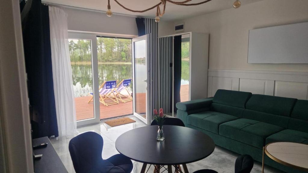 a living room with a green couch and a table at Mazury Apartamenty wodne tarasy Blue - Ruś in Ruś