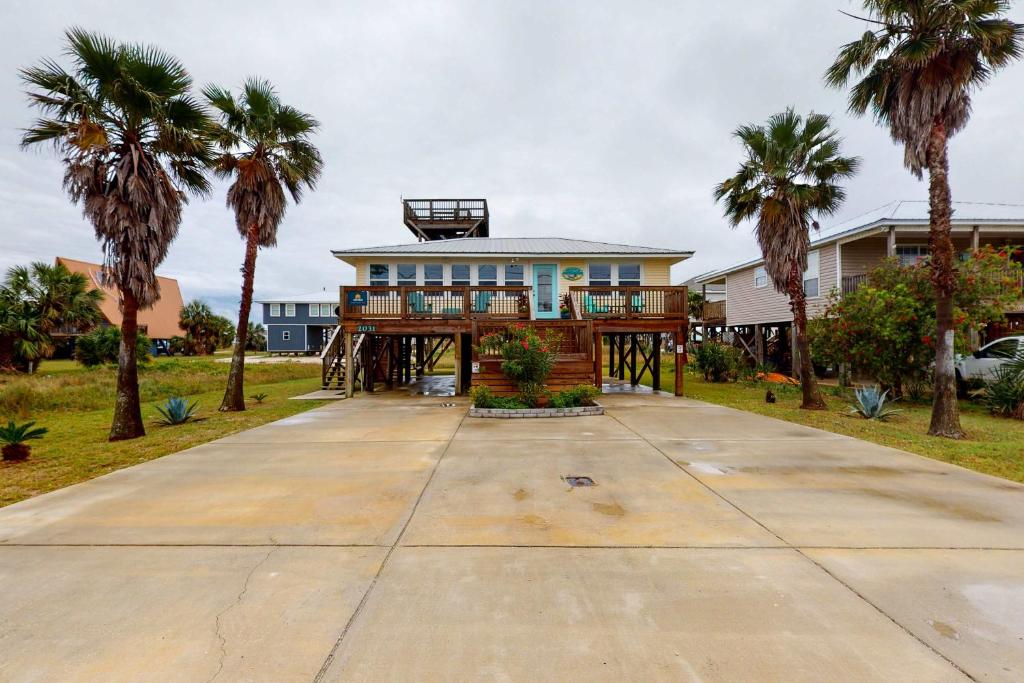 a house with palm trees in front of it at Mermaid Tales in Dauphin Island