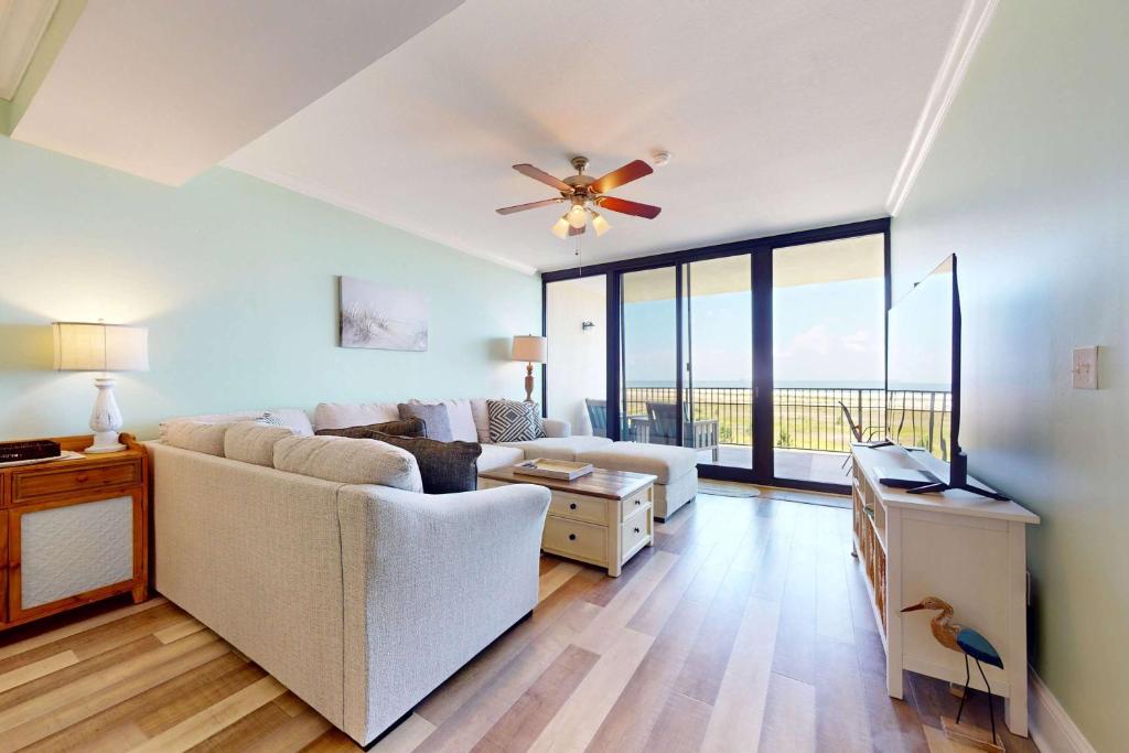 a living room with a couch and a ceiling fan at Beachfront condo with pool private balcony and laundry in Dauphin Island