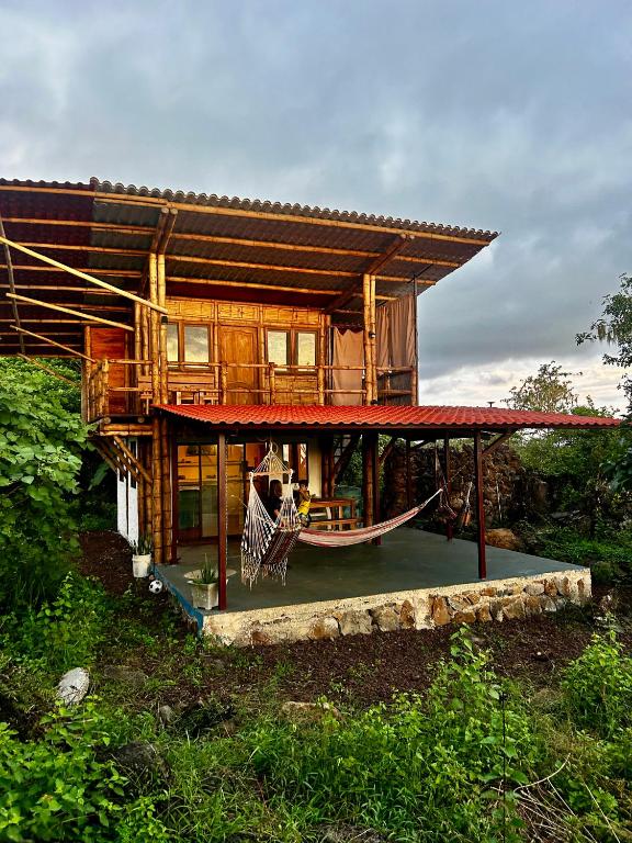 a house with a hammock and a boat in front of it at Highland Bamboo Cabin, San Cristóbal Galápagos in San Cristóbal