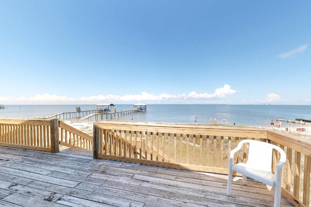a white chair sitting on a deck near the beach at Little Grand Hotel in Dauphin Island