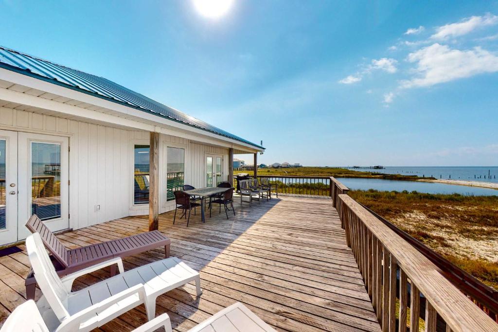 a house with a wooden deck with a table and chairs at Sunset Beach in Dauphin Island