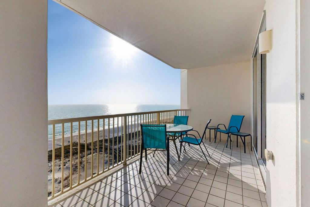 a balcony with a table and chairs and the ocean at Spacious beachfront condo with full kitchen shared pool and beach access in Gulf Shores