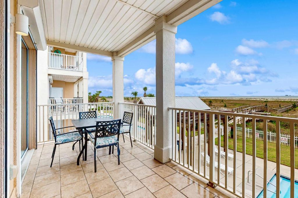 a patio with a table and chairs on a balcony at Gulf-Front Condo with Balcony Shared Pools and Beach Access in Dauphin Island