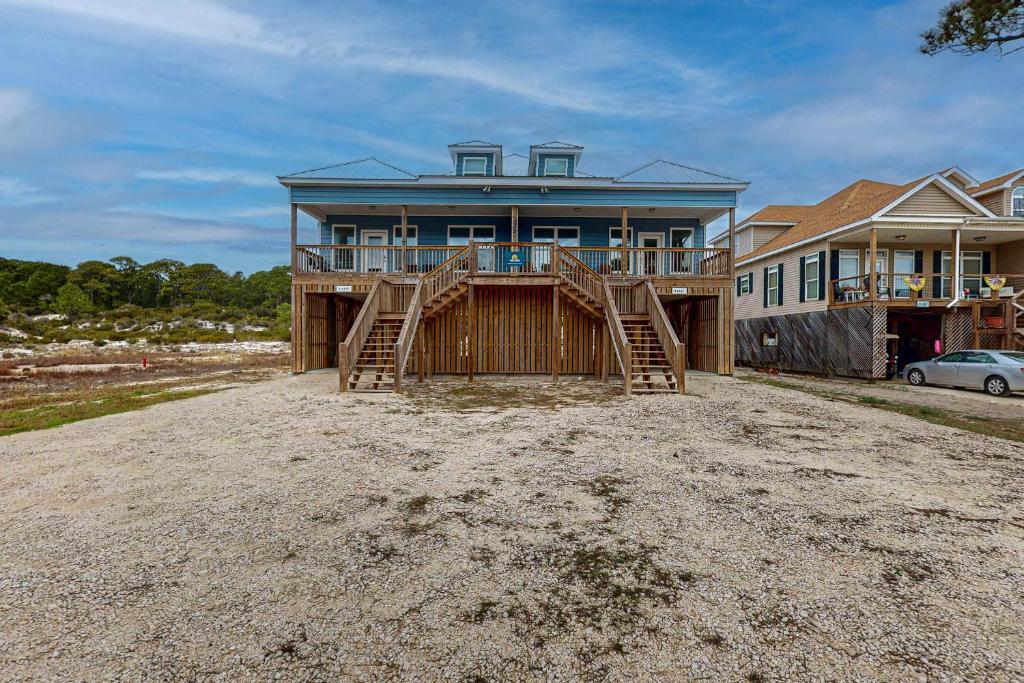a house with a large front porch and a driveway at Gulfview duplex with panoramic views large balcony and internet in Dauphin Island