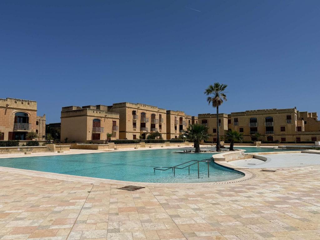 a large swimming pool in front of a building at Fort Chambray Gozo 2BDR Apartment in Għajnsielem