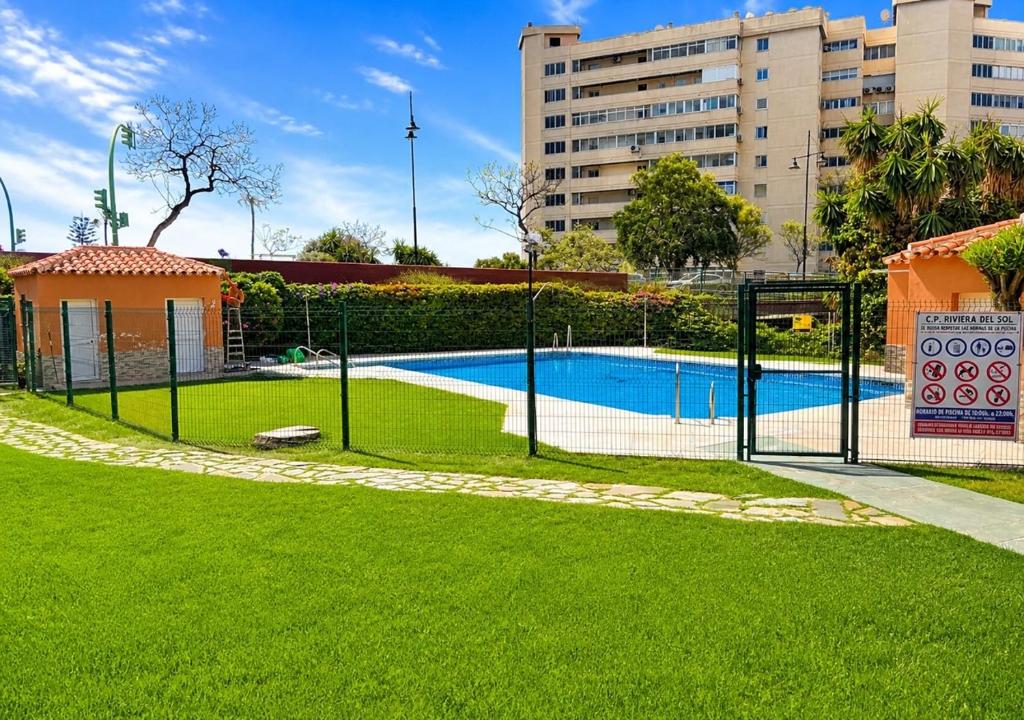 a fence around a swimming pool in a park at Estudio con piscina y jardines a 2 min de la playa - Fuengirola in Fuengirola