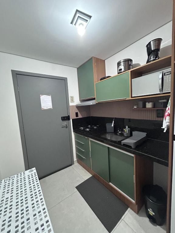 a kitchen with green cabinets and a black counter top at Flat Só Alegria in Cabedelo