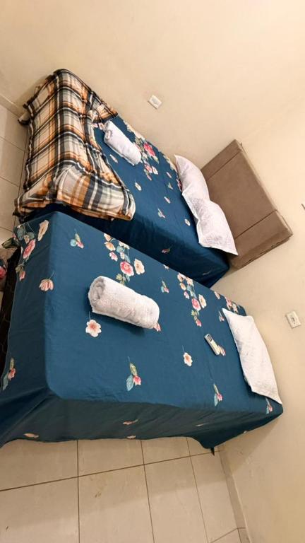 a bed with a blue comforter with flowers on it at Casa Mobiliada 4 camas e 2 quartos in Juazeiro do Norte