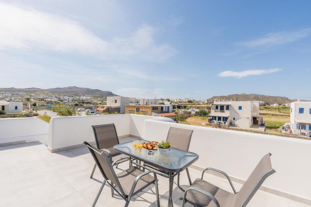 a patio with a table and chairs on a balcony at Vivens Mykonos Studios & Suites in Ano Mera