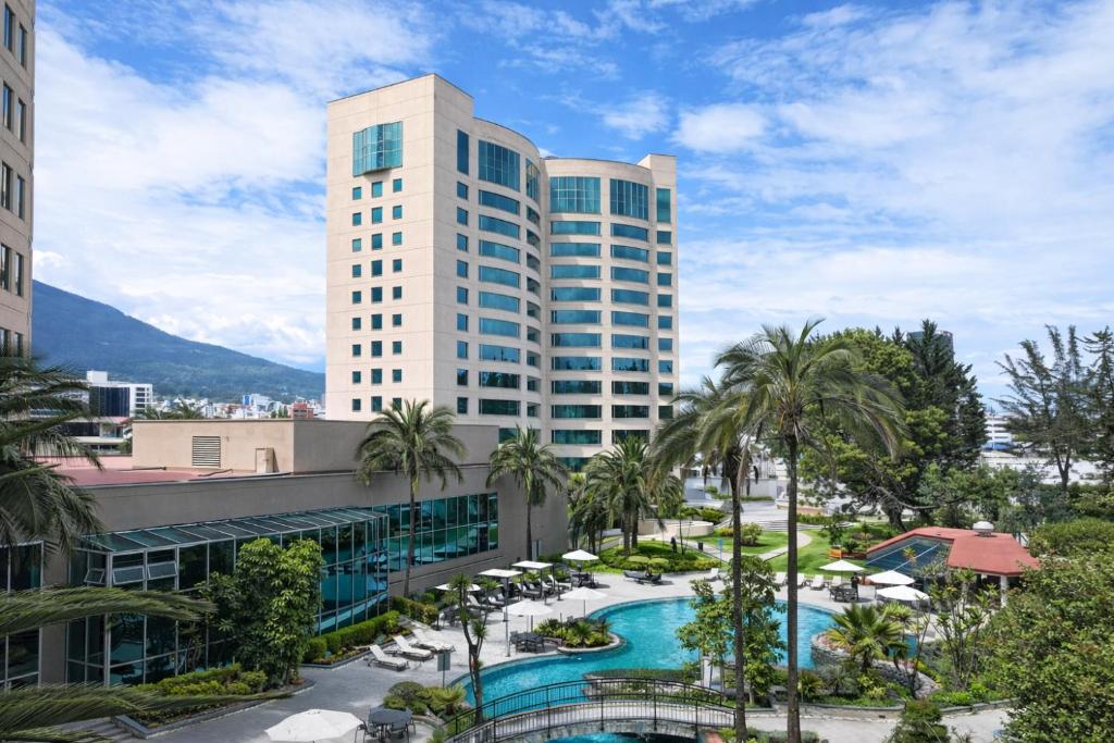a view of a hotel with a pool and palm trees at Torres de Suites by InAmazonas in Quito
