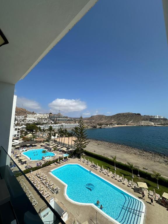 a view of the pool and beach from the balcony of a hotel at BH Cura marina 2 in Mogán