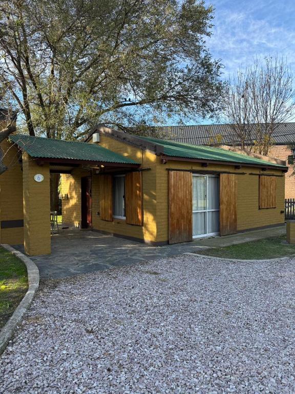 a yellow house with a driveway in front of it at Cabañas Ojo de Agua in Sierra de la Ventana