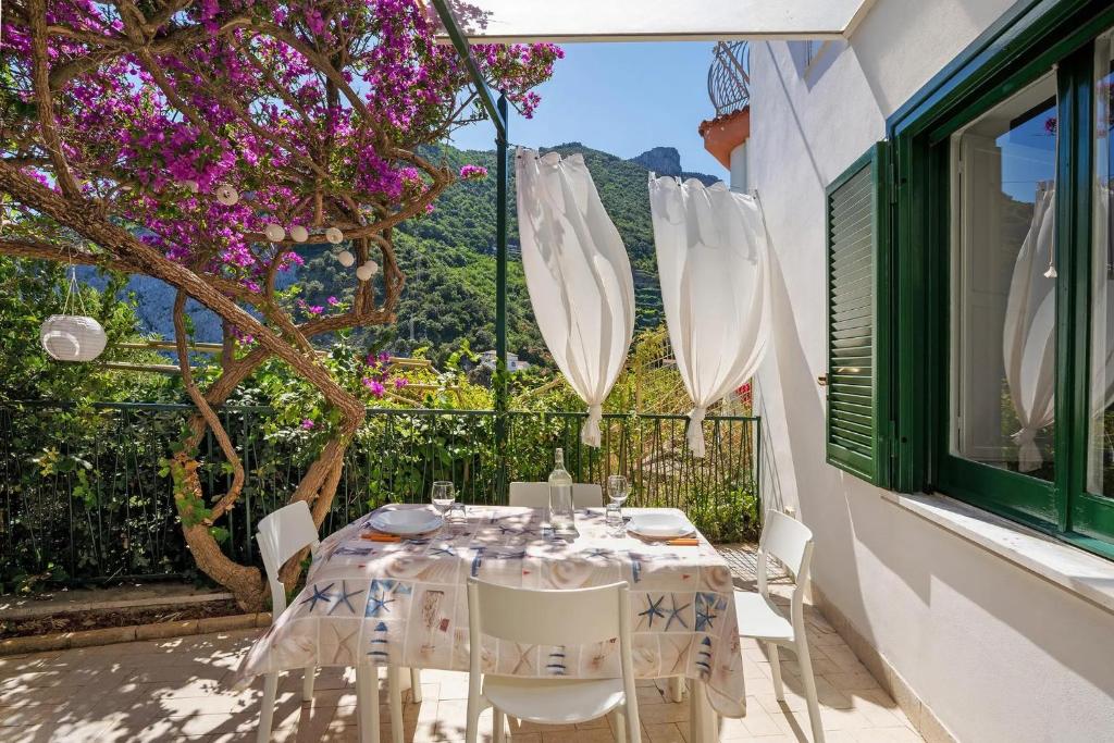 a white table and chairs on a balcony with a tree at Blue & Green Apartments in Erchie