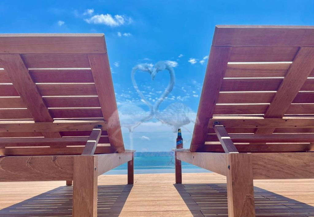 two wooden benches sitting on a pier with a peacock at Private Suite, Walk to the Beach, Oceanview Rooftop Pool, WiFi StarLink in Puerto Morelos