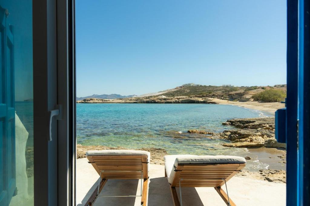 two chairs sitting on a balcony looking out at the ocean at Thavma Beach House in Mytakas