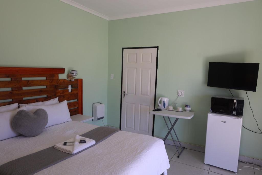 a bedroom with a bed with a tv on the wall at Bernliz Guest House in Bokong