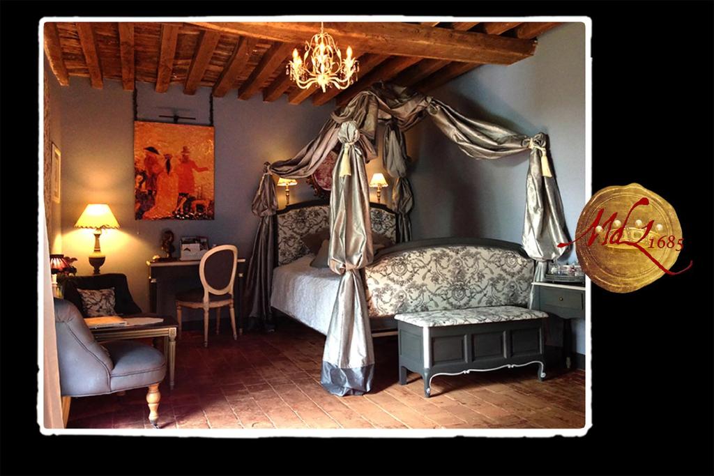 a bedroom with a canopy bed and a chair at Manoir de Livet in Saint-Germain-de-Livet