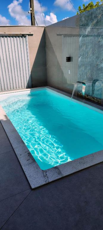 a blue swimming pool with a water fountain at Casa praia ótimo preço in Prado