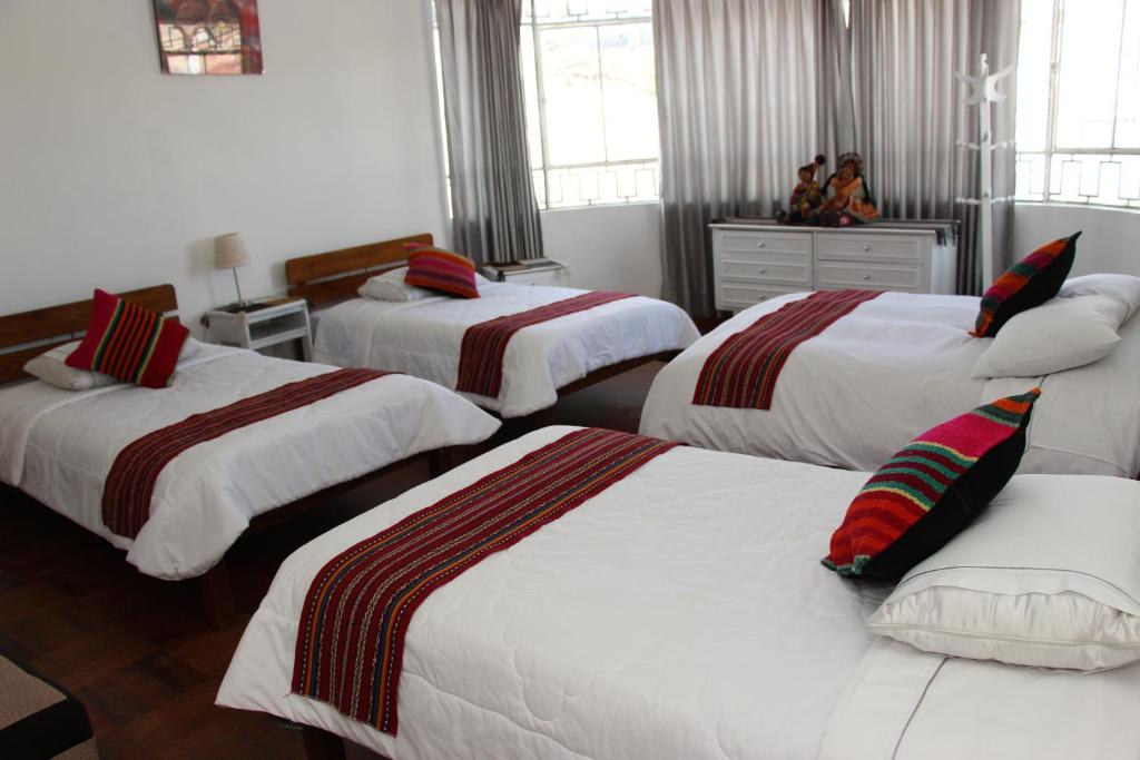 a bedroom with three beds with red and white sheets at Don Andre House in Cusco