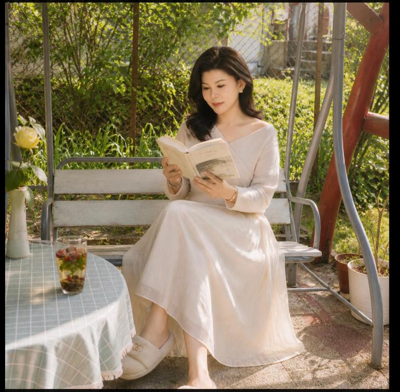 a woman sitting on a bench reading a book at Panorama Hills Villa in Budapest