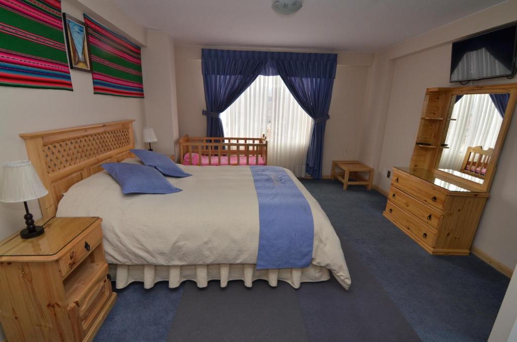 a bedroom with a large bed with blue pillows at Almudena Apart Hotel in La Paz