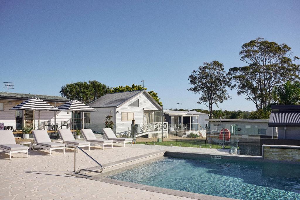 a swimming pool with lounge chairs and a house at The Mook Mollymook in Mollymook