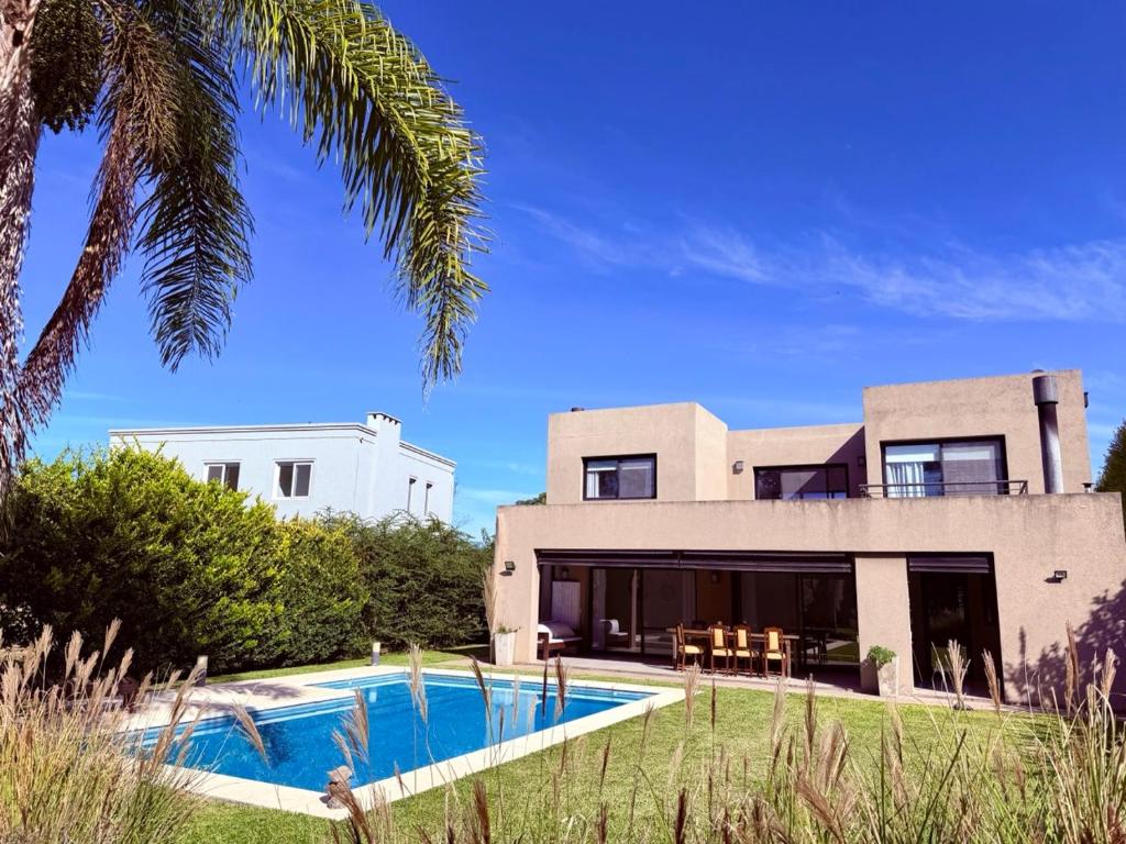 an exterior view of a house with a swimming pool at Casa con piscina en Estancias del Pilar, 3 dormitorios, jardín y parrilla in Pilar
