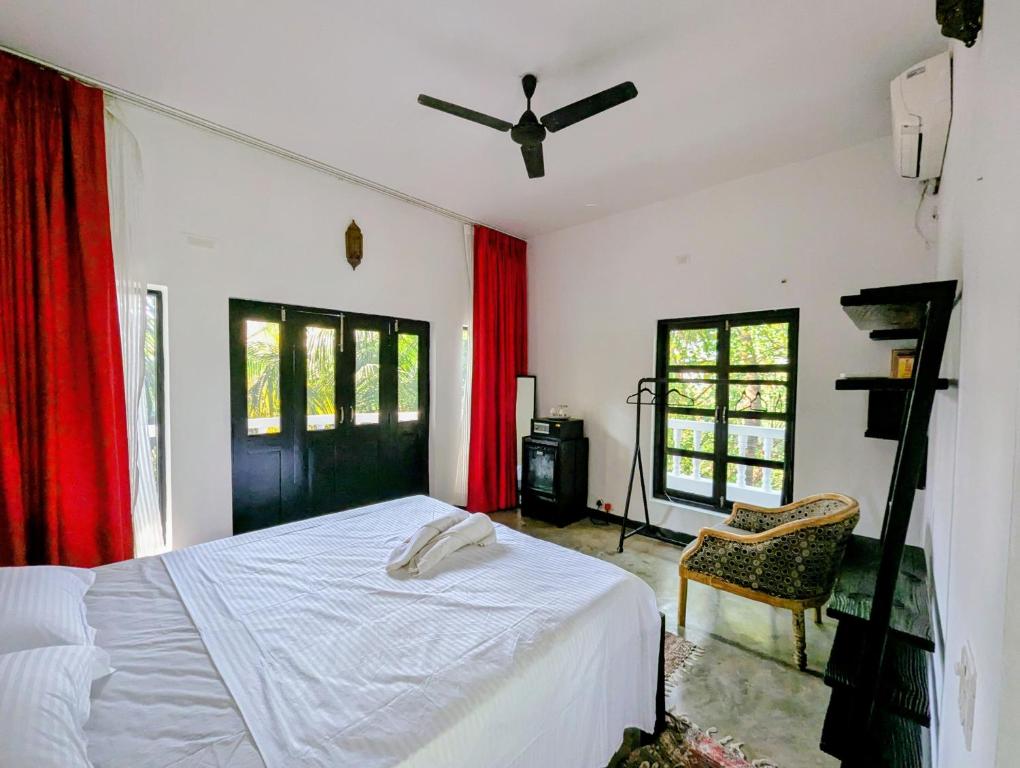 ein Schlafzimmer mit einem weißen Bett und roten Vorhängen in der Unterkunft The Double V Experience in Arambol