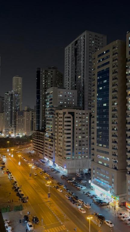 a city at night with cars parked in front of tall buildings at Sharjah Room in Sharjah