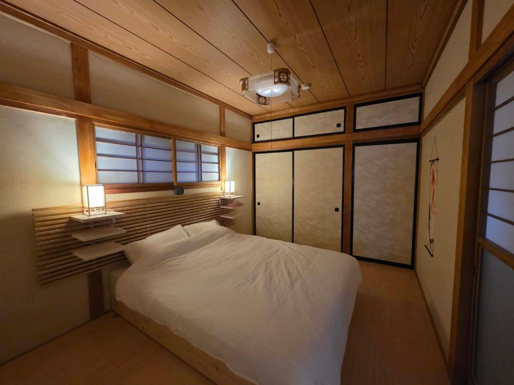 a bedroom with a large white bed and windows at GateFuji Fujisan Station in Fujiyoshida