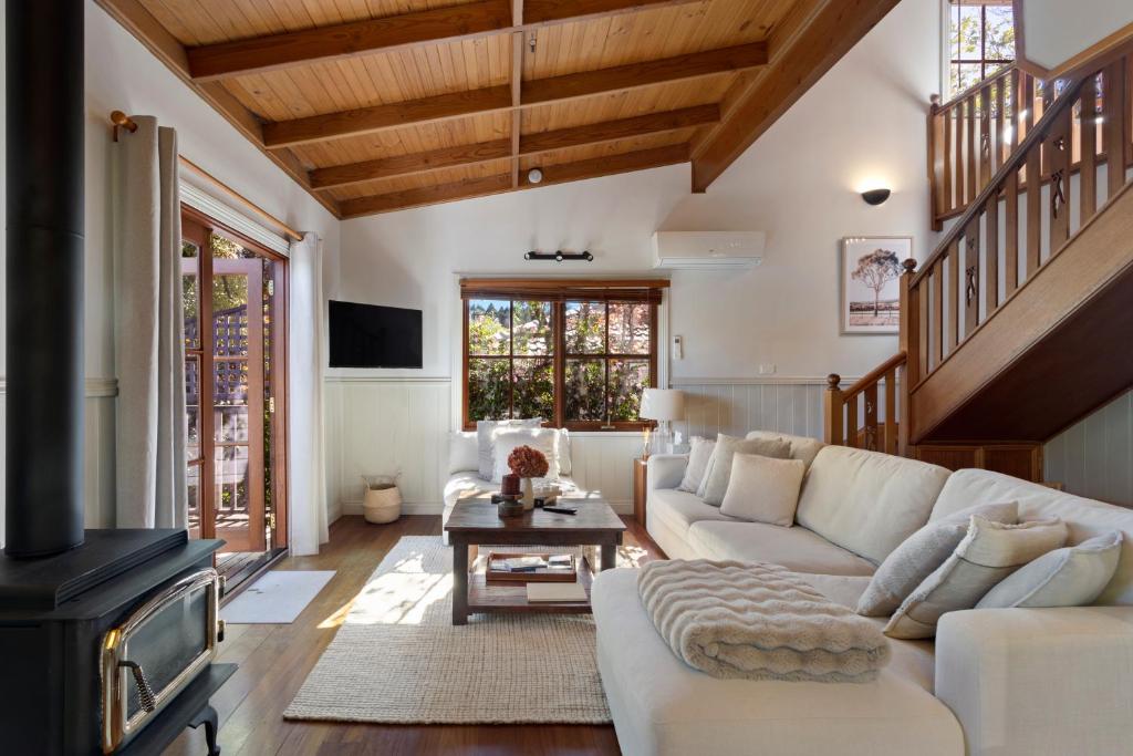 a living room with a white couch and a fireplace at Leura Lodge in Leura