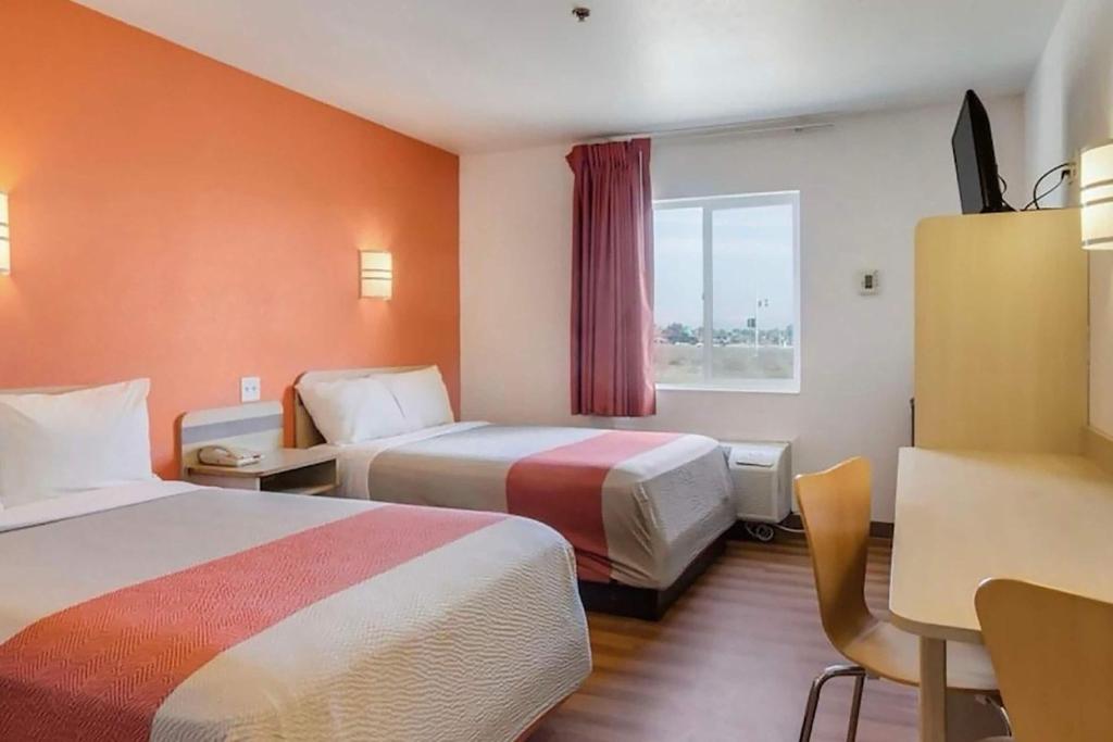 a hotel room with two beds and a desk at Howard Johnson by Wyndham Lemoore Near Naval Air Station in Lemoore