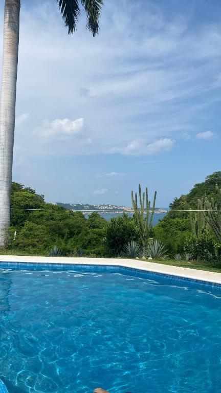 a blue swimming pool with a view of the ocean at Casa Palma in Santa Cruz Huatulco