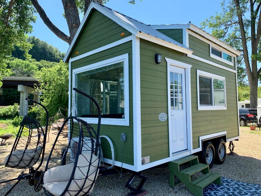 a green and white tiny house with a swing at The River's Edge (Tiny Home 3) in Bellevue