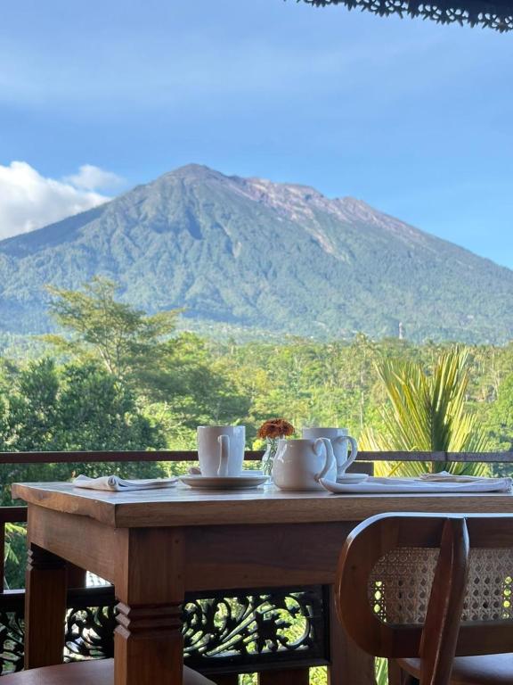a table with cups and saucers on it with a mountain at Artala Villa & Restaurant in Besakih